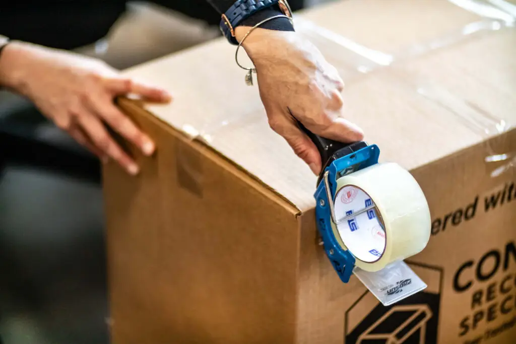 An employee using tape dispenser over a box